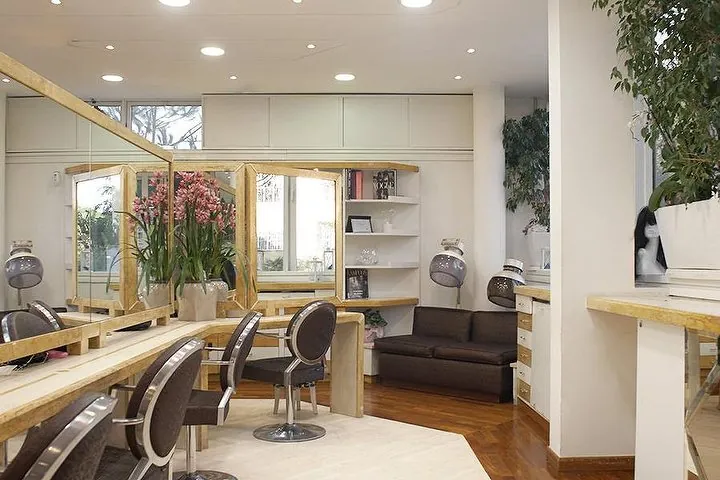 Il salone: postazioni in legno chiaro, poltrone scure, specchi con cornice dorata e orchidee rosa