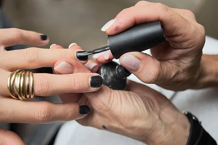Smalto nero steso sulle unghie durante una manicure